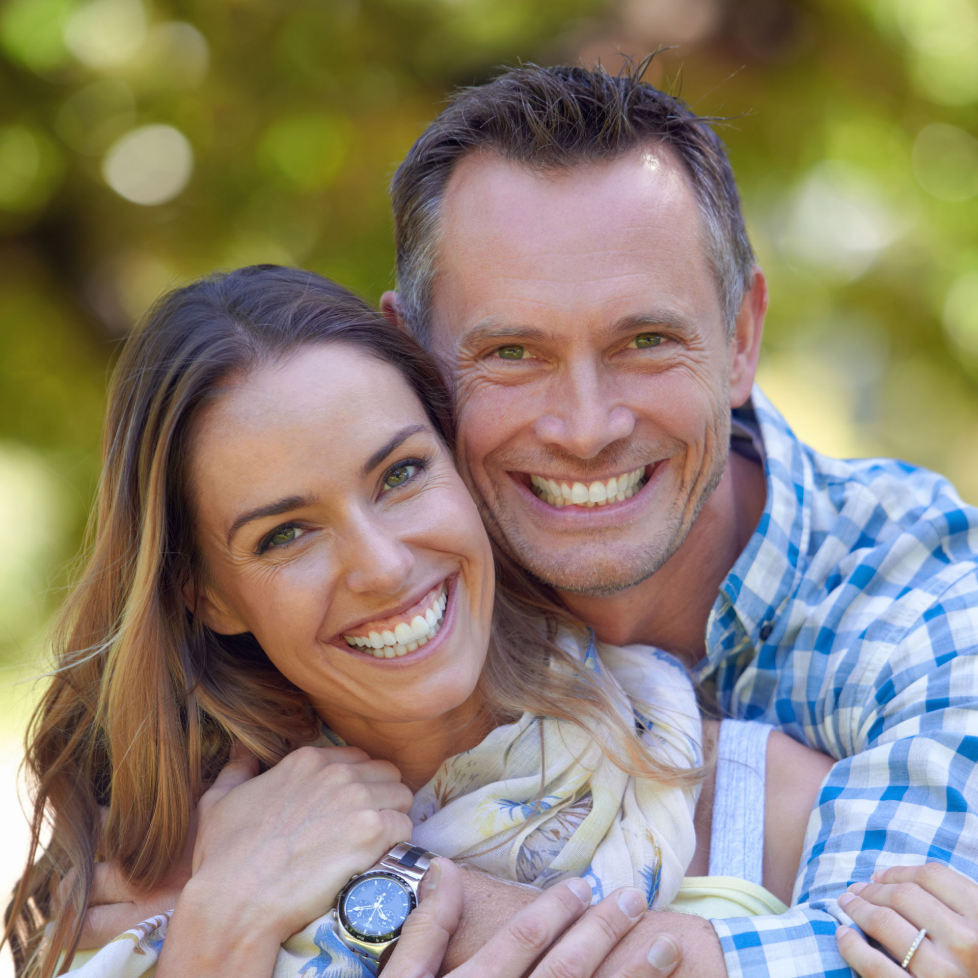 middle-aged couple hugging and smiling at camera
