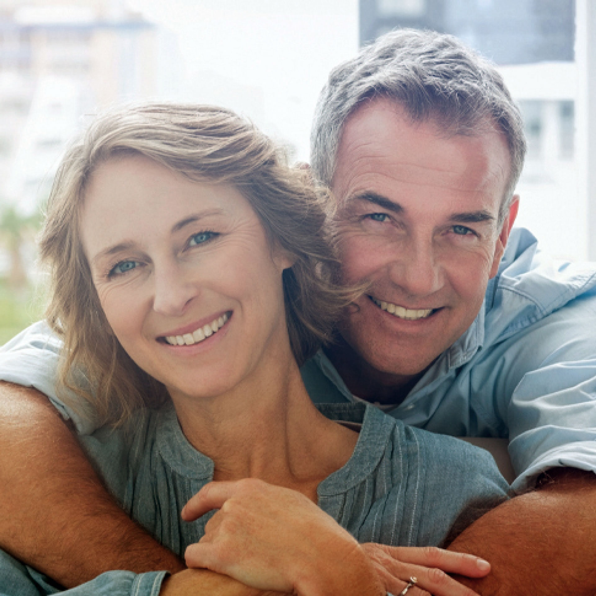 middle-aged couple hugging and smiling at camera